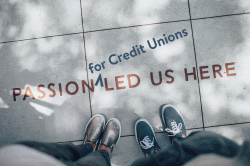 a photo taken looking down at two sets of feet on a sidewalk with the words "Passion for Credit Unions Led Us Here."